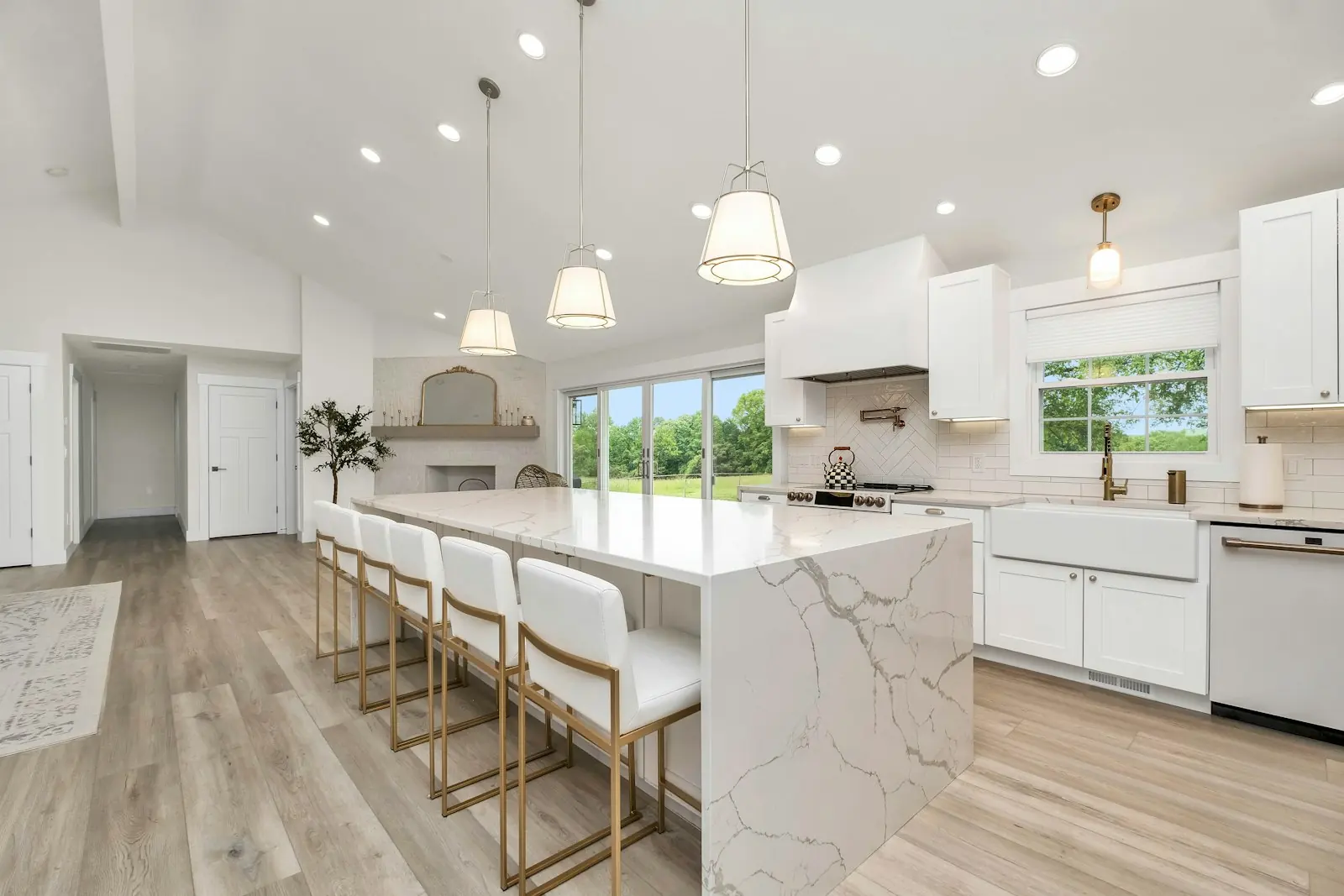 A bright open-plan kitchen with a stone island, pendant lighting and windows onto the garden